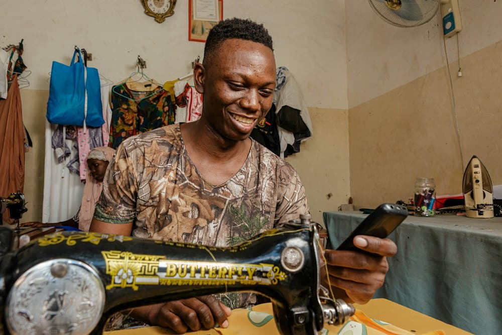 Young tailor smiling at his sewing machine