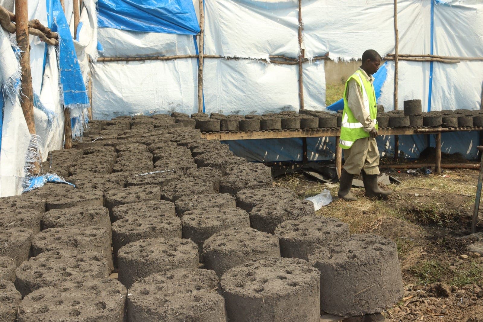 Worker walking past rows of moulded blocks drying at a production site